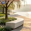 Banqueta curva de terrazo para rodear árboles a lo largo del paseo fluvial, hormigón visto, macizo de flores irregular, paisaje de jardín exterior