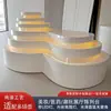 Soporte de exhibición de isla escalonado multicapa iluminado superficie curva de onda personalizada pintura horneada de alto brillo mesa de exhibición gabinete central de tienda showroom