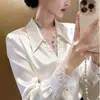 Este año, las camisas de alta gama con exquisitos diseños y adornos de encaje son tendencia. Estas camisas únicas y hermosas de satén blanco son perfectas para mujeres en las temporadas de primavera y otoño.