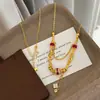 Colar banhado a ouro com detalhes em ouro areia e rubi, projetado para durar sem desbotar, apresentando uma corrente delicada e luxuosa para a clavícula com um pingente de trevo de quatro folhas