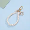 Llavero de correa de teléfono de perlas estilo Chanel para niñas con lazo en forma de corazón, flor y colgante de metal, accesorio para bolso