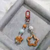 Hebilla de puerta G05 nuevo acrílico hueco brillante estrella de cinco puntas llavero para coche colgante crema dos colores campanilla a juego