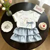 Elegante Conjunto de Camiseta de Manga Corta Fina de Verano y Falda Corta a Cuadros para Bebés Niñas Nuevo 2026 Camiseta de Dibujos Animados Conjunto de Dos Piezas