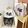 Nuevo Estilo Conjunto de Dos Piezas para Bebé Niño Camiseta de Algodón con Cuello Redondo Estilo Graffiti y Pantalones de Mezclilla Lavados a la Arena Venta al por Mayor desde el Fabricante Original