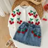 Conjunto de primavera y otoño para niños europeos y americanos: suéter de punto de cereza + minifalda vaquera vintage, ropa elegante y a la moda para bebés y niños en stock