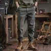 Nueva colección primavera 2026: Pantalones de trabajo modernos, minimalistas y casuales para hombre, con un corte relajado y tobillos cónicos, en un estilo retro.
