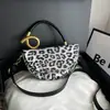 Bolso de mano de diseño de nicho de alto valor con estampado de leopardo y retazos para mujer, nuevo y elegante para el verano 2026, bandolera cruzada de un solo hombro tipo silla de montar