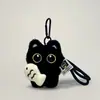 Llavero y colgante para mochila de gato negro sin dientes blanco y negro, lindo y adorable gato negro de ojos grandes sosteniendo un pez pequeño de peluche decoración