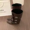 Botas femininas pretas de bico fino, salto grosso e perna larga, com um estiloso design de fivela de cinto, estilo montaria de cano alto, e comprimento que não chega ao joelho, em estilo cowboy ocidental