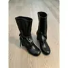 Nova coleção 2026: Botas femininas de cano médio com tiras e saltos grossos, perfeitas para outono e inverno, apresentando um design emagrecedor com detalhes plissados e um visual de salto alto estilo equestre.