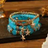 Pulseras multicapa al por mayor, juego de cuatro piezas de joyería con cuentas de artesanía en vidrio, juego de pulseras elásticas, accesorio de mano con soporte de flor de hierro