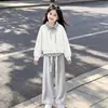 Atuendo elegante y moderno para niñas 2026: top de moda tipo dos piezas con un cuello elegante, combinado con pantalones sencillos y casuales, un conjunto de dos piezas versátil