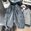 Roupas novas para crianças 2026, coleção de outono para meninos, calças estilo workwear com bolsos grandes, jeans do papai, jeans de perna curva, atacado