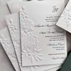 Elegantes y estilosas invitaciones de boda con relieve floral 3D y iniciales en pan de oro, hechas a medida por la fábrica