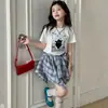 Traje de Falda de Manga Corta de Verano para Niñas 2026 Nuevo Estilo Moda Infantil Falda a Cuadros Asimétrica Conjunto de Dos Piezas Transfronterizo