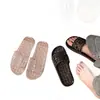 Pantuflas de gelatina cristalina de moda para mujer, con diseño hueco, drenaje completo, adecuadas para el baño, antideslizantes, de secado rápido y estilo de una tira negra.