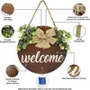 Letrero de bienvenida de madera marrón para uso doméstico, decorado con plantas verdes y un lazo