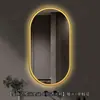 Espejo de baño inteligente ovalado en stock con lijado exterior e iluminación LED translúcida, adecuado para montaje en pared de baño y proyectos hoteleros, con opciones de personalización.
