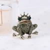Broche de rana estilo príncipe de dibujos animados retro europeo y americano, temperamento femenino, broche de metal con forma de animal que gotea aceite, accesorios de ramillete.