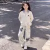 Conjunto elegante de dos piezas: top estilo universitario, oversized, de manga larga, con un diseño moderno, combinado con pantalones casuales de estampado retro de mariposas.