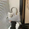Bolso bandolera elegante y chic de un solo hombro, con un diseño minimalista y una forma pequeña y cuadrada.. Esta es la colección de verano 2026 de bolsos de mujer de moda