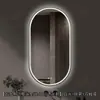 Espejo de baño inteligente ovalado en stock con lijado exterior e iluminación LED translúcida, adecuado para montaje en pared de baño y proyectos hoteleros, con opciones de personalización.