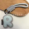 Venta al por mayor transfronteriza de llaveros japoneses y coreanos con letras en inglés, dijes para bolso de cuero dopamina, pequeños accesorios y regalos