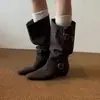 No entanto, o novo estilo de botas de cavaleiro apresenta um cano largo, uma fivela de cinto de couro, um acabamento em camurça, um efeito emagrecedor, um salto grosso, uma biqueira quadrada e um comprimento até a panturrilha.