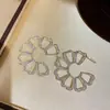 Pendientes de botón flor hueca metálica de tendencia europea y americana, pendientes simples de moda transfronteriza, pendientes de lujo ligero de alta gama para mujer