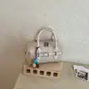 Bolso tejido de patrón cuidadosamente seleccionado para mujer, bolso de hombro de PU de color liso fresco, bolso cruzado versátil y simple con colgante para el verano 2026