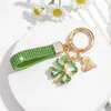 Bestseller transfronterizo europeo y americano: Lujoso llavero de trébol de cuatro hojas con adornos de diamantes completos, brillante y elegante, con un colgante de cordón de cuero