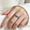 Anel luxuoso e elegante cravejado de esmeraldas com cravação completa de diamantes, apresentando um design sofisticado e moderno, perfeito para o dedo indicador e fácil de combinar com qualquer roupa.
