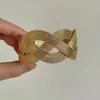Brazalete abierto tejido de metal retorcido dorado brillante estilo antiguo vintage con un toque de alta gama