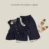 Conjunto de dos piezas de estilo suave para niña de principios de otoño: chaleco de cuello redondo con botones de madera, bajo con volantes y pantalones de pierna ancha ribeteados con encaje para salir