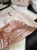 Falda corta de lana estilo coreano con hebilla dorada para mujer 2026 Otoño/Invierno Nueva falda plisada de línea A versátil de cintura alta adelgazante anti-exposición