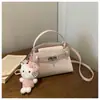 Mini bolso trapecio de estilo coreano con suave patrón de piedra, cierre metálico y decoración de cinturón, bolso cruzado de nicho