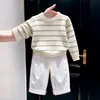 Nueva colección de otoño/invierno 2026 para niños estilo coreano: Suéter de punto color hueso con rayas verdes, combinado con pantalones blancos de pierna ancha - un conjunto de dos piezas