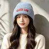 Nuevo gorro de punto bordado estilo coreano para mujer, cálido versátil para otoño e invierno, con bordado de letras, para exteriores, a prueba de frío, protege los oídos, de lana