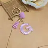 Llavero de letra inglesa rosa, un accesorio lindo y moderno con un pompón esponjoso y un borla, perfecto para proyectos de bricolaje y como charm para bolso para mujeres