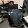 Bolsa de balde casual de grande capacidade para mulheres, novo modelo outono 2026, alto valor estético, cor sólida, design de rebite, bolsa de ombro simples para o dia a dia