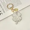 Nova Chaveiro Trevo de Quatro Folhas Cheio de Diamantes de Argila de Cristal Exquisito Pingente de Carro com Pedras Strass Embutidas Bolsa de Luxo Leve