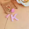 Chaveiro de letra inglesa rosa, um acessório fofo e moderno com um pompom fofo e uma franja, perfeito para projetos DIY e como pingente de bolsa para mulheres