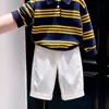 Ropa infantil estilo coreano 2026 colección otoño e invierno nueva: Suéter de punto con cuello polo a rayas azul marino y pantalones casuales blancos para niños
