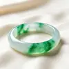 Pulsera de jade de alta calidad con una textura clara y helada y vibrantes patrones florales verdes. El jade es excepcionalmente claro y el diseño floral es vívido, realzando la elegancia de quien lo lleva.. Venta al por mayor de exquisitos brazaletes de jade para mujer