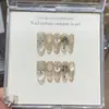 Un Diseño de Uñas Cat-Eye con Gris Champaña, Isla Dorada de los Sueños, Estilo Mil Dorados, Sonrisa Captadora de Luz, Explosión Estelar Pintada a Mano y Pedrería Apilada