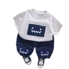 Comercio Exterior Ropa Infantil al por Mayor 2025 Nuevo Verano Lindo Cuadrado Cara Sonriente Traje de Manga Corta Camiseta Pantalones Cortos Traje