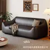 Sofá de estilo de mediados de siglo, color blanco roto, de piel sintética, con reposabrazos redondeados de forma única, cojines de asiento segmentados y diseño de pie, adecuado para una sala de estar como sofá de línea recta