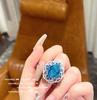Anillo Huguang Shui Ying Aqua Blue Love Gem, diseño chapado en oro de 18 quilates, color Baodan, con forma de flor de circón