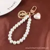Novo Pulseira de Pérolas Criativa, Chaveiro Pingente de Liga Coração de Pêssego Fofo, Acessório de Metal Cabeça de Beleza, Bolsa Decorativa Feminina