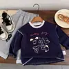 Camiseta de algodón puro para niños, modelo primavera y otoño 2026 para bebés y niños pequeños, top de dibujos animados graffiti estilo ins, camiseta interior de manga larga para niños